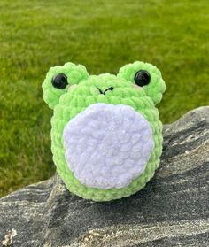 a stuffed frog sitting on top of a rock