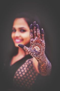 a woman is holding her hand up to show off her hendi and wrist tattoo