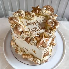 there is a heart shaped cake with shells on the top and gold decorations around it