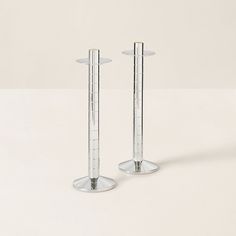 two tall clear candlesticks sitting next to each other on a white table top