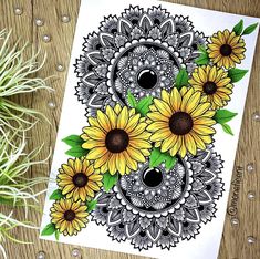 sunflowers with green leaves on a table next to a potted plant and an ink drawing