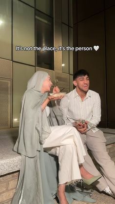 a man and woman sitting next to each other in front of a building with the words it's not the place, it's the person