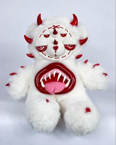 a white stuffed animal with red teeth and fangs on it's face is holding a toothbrush