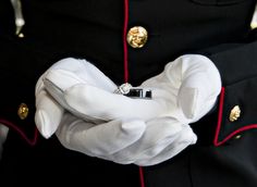 a close up of a person wearing a uniform and holding a wedding ring in their hand