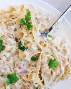 a white plate topped with pasta covered in sauce and garnished with parsley