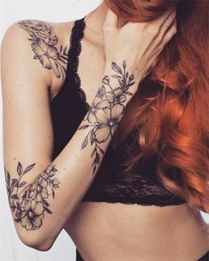 a woman with red hair and tattoos on her arm holding her hand to her face