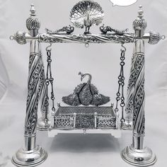 an ornate silver bed with two peacocks on it's sides and a thought bubble above the bed