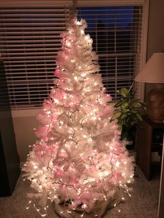 a white christmas tree decorated with pink and white lights