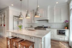 a large kitchen with white cabinets and wooden floors