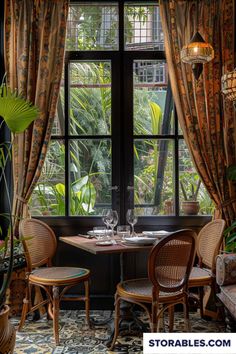 a table with two chairs and a wine glass on it in front of a window