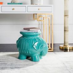 an elephant shaped vase sitting on top of a rug in front of a white table