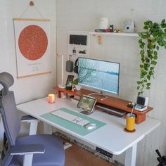 a desk with a computer monitor, keyboard and mouse next to a plant on the wall