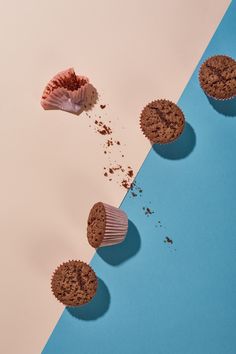 three chocolate muffins on a blue and pink background with one broken in half