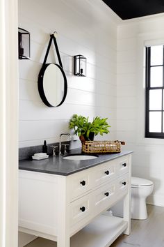 a white bathroom with black counter top and toilet