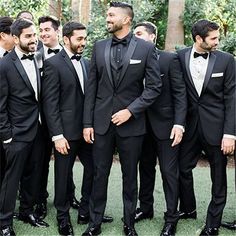 a group of men in tuxedos standing next to each other on the grass