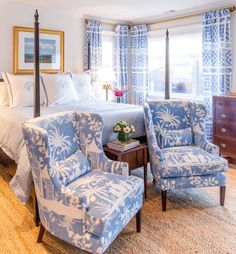 a bed room with a neatly made bed and two chairs in front of the bed