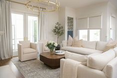 a living room filled with furniture and a chandelier hanging from the ceiling over a fire place