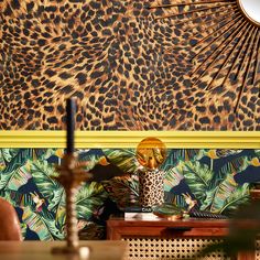 a leopard print wallpaper in a living room next to a table with a vase on it