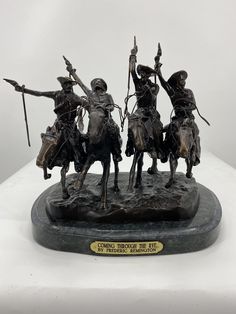 a bronze statue of three men on horseback with spears in their hands and two holding staffs