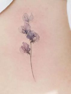 the back of a woman's stomach with purple flowers on her left side ribcage