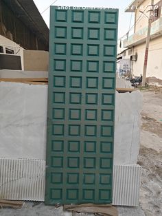 a large green door sitting on top of a pile of cement next to a building