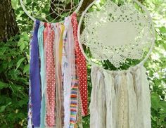 several different colors of fabric hanging from a tree in front of some green leaves and branches