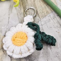 a crocheted flower keychain with green and white yarn