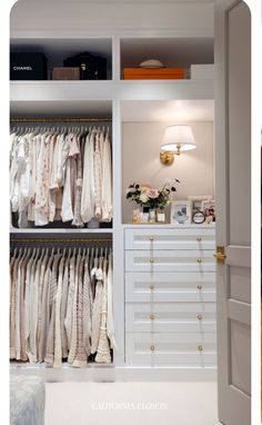 an open closet with clothes hanging on the wall, and a lamp next to it