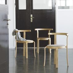 two wooden chairs sitting next to each other in front of a door