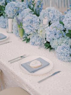 the table is set with blue flowers and silverware