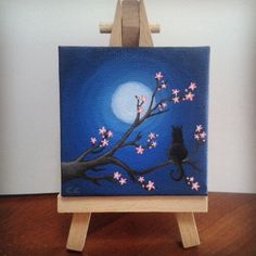 a cat sitting on a tree branch in front of a full moon with pink flowers