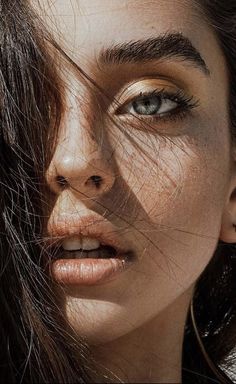 a close up of a woman with large hoop earrings on her head and hair blowing in the wind