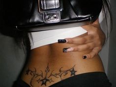 a woman with tattoos on her stomach holding a black purse