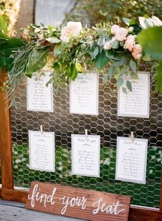 a wooden sign with seating cards attached to it that says find your seat and flowers