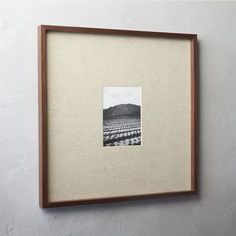 an old photo hanging on the wall with a wooden frame and white paper underneath it