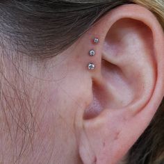 a woman's ear with three small diamond studs