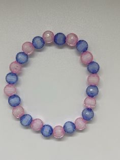 Material: Clear String Color: Light Pink and Blue/Purple Type: Bracelet Style: Glamorous Blue Crystal Bracelet With Colorful Beads, Gift Blue Stretch Bracelet With Polished Beads, Blue Crystal Bracelet With Polished Round Beads, Blue Stretch Bracelet With Polished Beads As Gift, Pink Hand-strung Bangle Stretch Bracelet, Blue Stretch Bracelet With Large Beads, Blue Polished Beads Bracelet, Blue Polished Beads Round Bracelet, Blue Round Beaded Bracelets With Faceted Beads