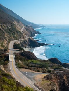 an empty highway on the side of a cliff near the ocean