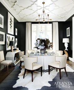 an elegant dining room with black walls and white chairs around a round table surrounded by framed pictures