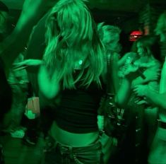 a group of people standing around in a room with green light on the walls and floor