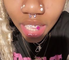 a close up of a person with piercings on their nose and tongue, wearing a black t - shirt