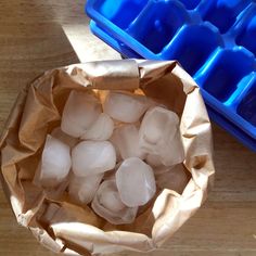 ice cubes in a paper bag next to an ice tray on a wooden table