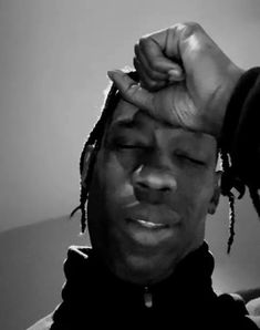 a black and white photo of a man with dreadlocks holding his head up