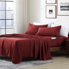 a bed with red sheets and white pillows