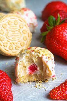 some strawberries and cookies are laying on a table together with one bite taken out