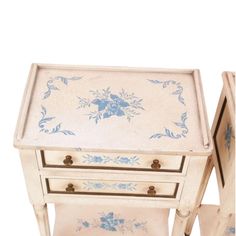 two white and blue painted tables with drawers on each side, one drawer has an open lid