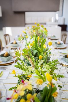 the table is set with yellow flowers and greenery for an elegant dinner or bridal party