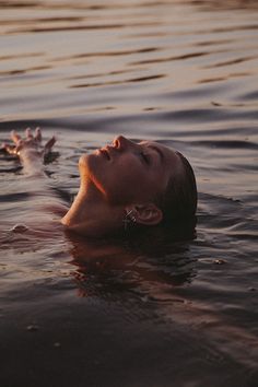 a person floating in the water with their head above the water's surface and one hand reaching for something