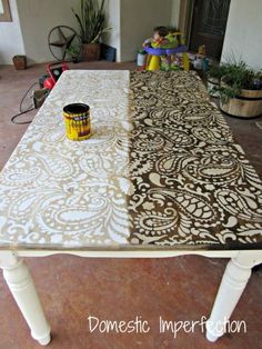 a table that has been painted with brown and white designs on it, next to a can of paint