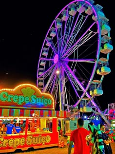 a ferris wheel and rides at an amusement park with people walking around the fairground